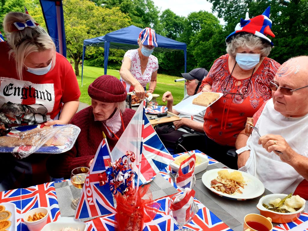 People eating at a table decorated with union jacks at a garden party