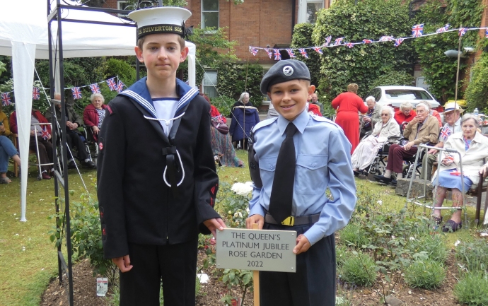 Two cadets in a garden with a sign that reads The Queen's Platinum Jubilee Rose Garden 2022